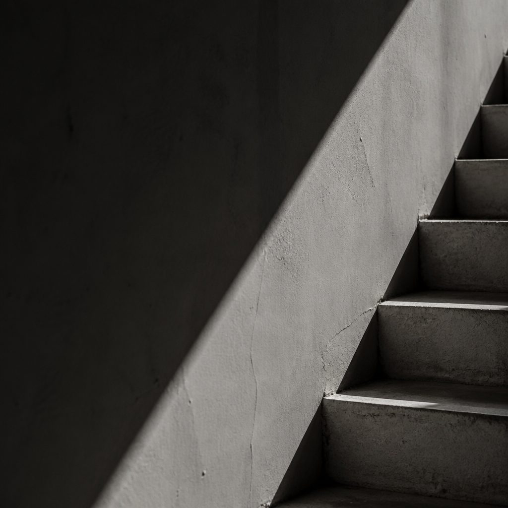 High contrast staircase photographed with a sharp diagonal shadow cast across the steps and wall